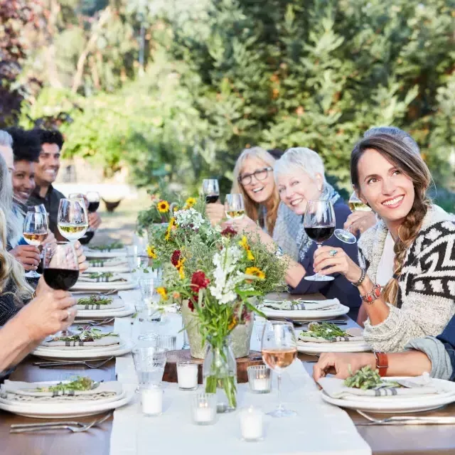 Des amis à une table partageant une dégustation de vin en plein air